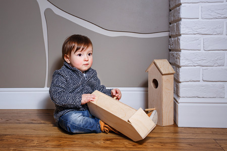 Little boy sits on the floor and playing with starling houseの写真素材