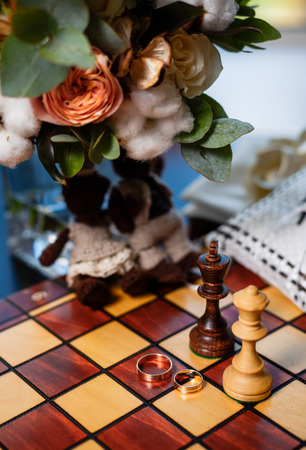 Wedding rings lie on a chessboard with chess pieces close shot closeupの写真素材