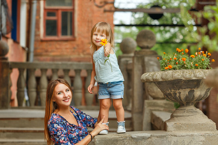 Mother and daughter for a walk in the city park. Kid is holding a flower.の写真素材