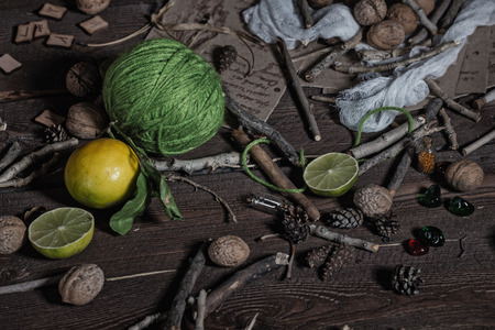Still life of ingredients for making potions witch. Nuts, sticks, scrolls, thread, runes, charms, pumpkin, lime, lemon, pine cones and other ingredients lie on a wooden table.の写真素材