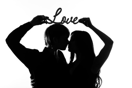 Young couple in love hugging each other, black and white photo. Are holding an inscription loveの写真素材