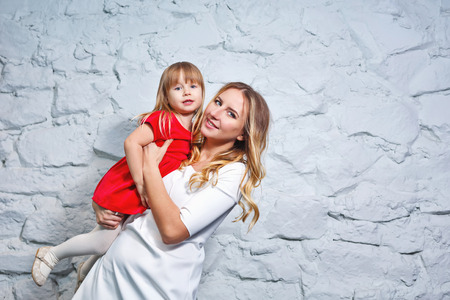 Young mother is holding her daughter, shot in the studio. The concept of family happiness.の写真素材