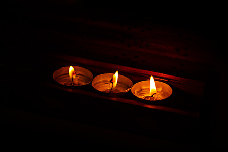 Three candles on a dark background in a warm light. The concept of a romantic relationship.の写真素材