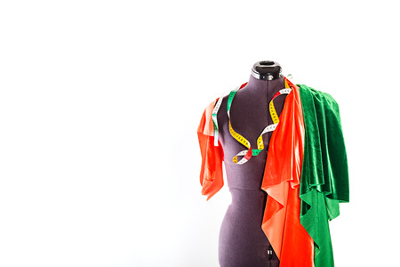 Mannequin with a piece of red and green fabric and measuring tape. The concept of fashion and fashion design.の写真素材