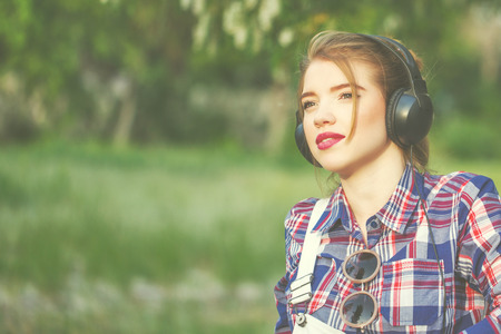 Portrait of pretty attractive hipster girl headphones. Warm toning. The concept of youth fashion.の写真素材