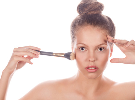 Portrait of a teen girl with Nude makeup, hair and clean skin holding a brush makeup. Isolated on white background.の写真素材