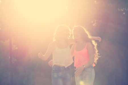 Best girlfriends hug. Girls dressed in the style of Pin-up girl. Hipster. Warm toning. Sunset. The concept of true friendship.の写真素材