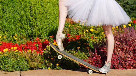 Legs of a ballerina on a skateboard. Feet shod in sneakers and pointes. Modern fashion. Photo closeup.の写真素材