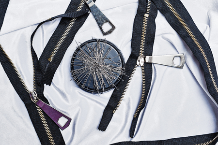 Zip, a needle lying on the silk cloth. The concept of needlework. Clothing design. Fashion houses. Items for sewingの写真素材