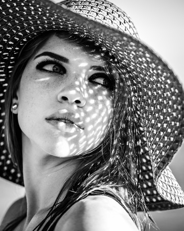 Pretty girl in a hat. The concept of summer vacation. Black and white photography. Shooting in low key.の写真素材