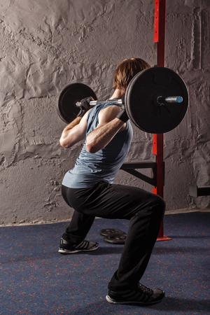 Man crouches down with a barbell. Healthy lifestyle concept. Fitness club.の写真素材