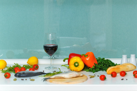 Still life. Ripe vegetables, bread, fish and wine on the kitchen table. Dinner time.の写真素材