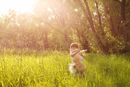Little Girl and Spitz. Girl hugging a pet standing in a meadow.の写真素材