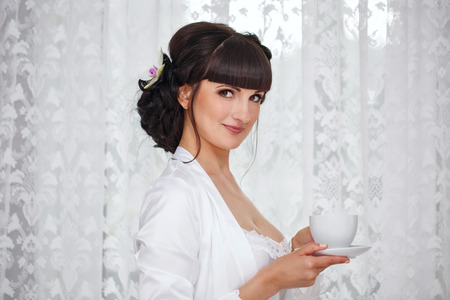 Cute girl drinking morning coffee in the bedroom. Good morningの写真素材
