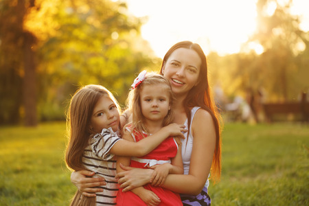 Family hug. Mother and two daughters together. On open air.の写真素材