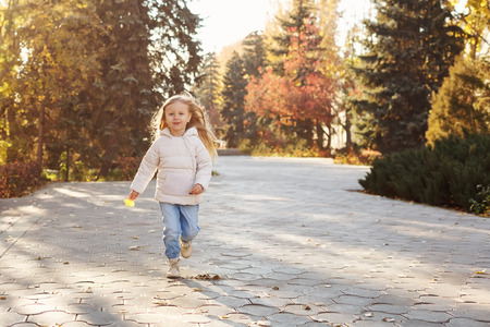 Little cute girl running in autumn park.の写真素材