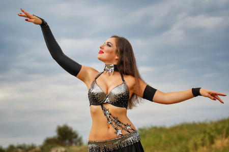 Oriental Beauty belly dancer. Nice girl in national dress dancing in the open air. Nomads.の写真素材