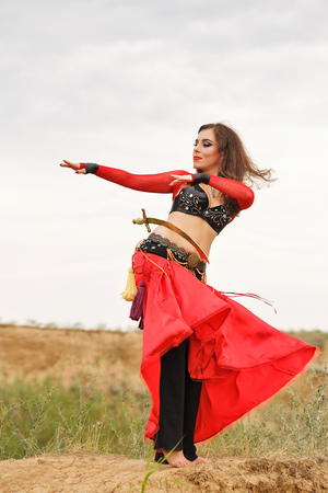 Oriental Beauty dance with a sword. Tribal style. Lovely girl in costume dancing outdoors. Nomads. Passionate dance.の写真素材