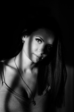Young attractive cute girl dramatic portrait. Black and white photography. Low key.の写真素材