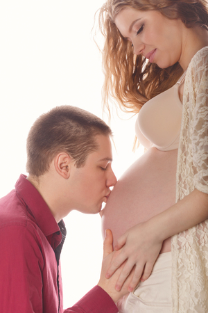 Husband kissing belly of a pregnant girl. Tenderness and love in the family. In anticipation of the baby.の写真素材