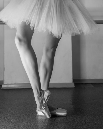 A ballerina in pointes and a pack warms up before the dance lesson. Long slender female feet. Classical ballet. Prima ballerina. Black and white photographyの写真素材