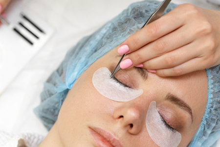 Beauty salon. The procedure of fastening the extended eyelashes. Shooting close-up. Aesthetic facial treatment. Expressive look.の写真素材