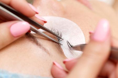 Beauty salon. The procedure of fastening the extended eyelashes. Shooting close-up. Aesthetic facial...