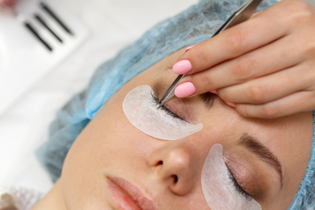 Beauty salon. The procedure of fastening the extended eyelashes. Shooting close-up. Aesthetic facial treatment. Expressive look.の写真素材