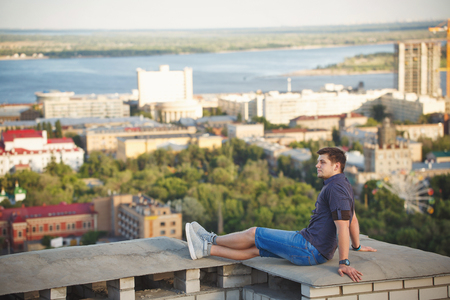 Roofer sits on the roof of a high-rise building and looks into the distance. Freedom and adrenaline.の写真素材