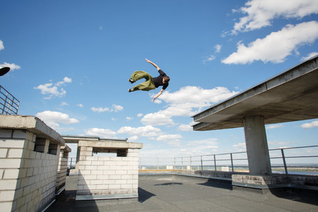 Man flips on the roof of high-rise building. Parkour. Active lifestyle. Roofer