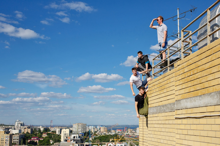 A group of roofer climbs the stairs to the roof. Active way of life in urban space. Courage and adrenaline.の写真素材