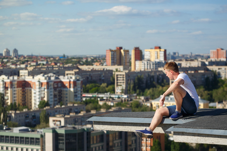 Roofer on the edge of the roof. A man looks at the city panorama from a high-rise building. Courage and adrenaline. Roofingの写真素材