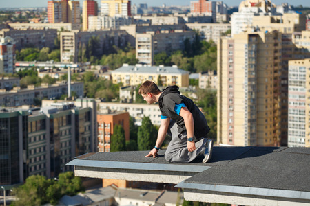 Roofer on the edge of the roof. A man looks down from a high-rise building. Courage and adrenaline. Roofing.の写真素材