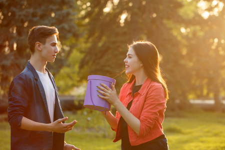 Date of teenagers. The guy gives a gift to his girlfriend. The girl is happy surprises.の写真素材