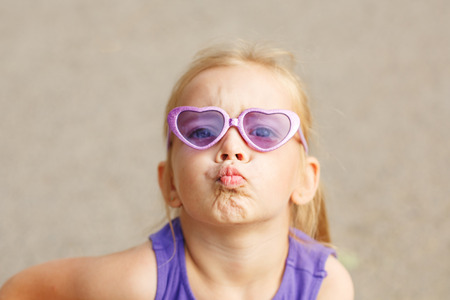A nice little girl in sunglasses. Portrait of a child. She sends an air kissの写真素材