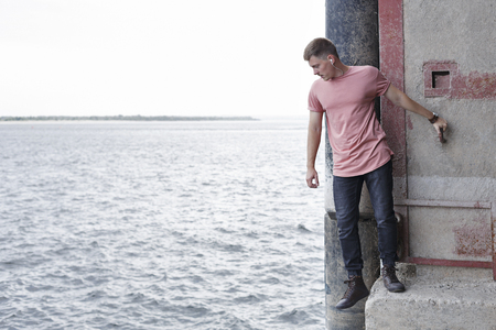 The guy listens to music standing on the pier. Youth fashion.の写真素材