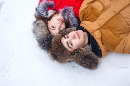 Couple in love. Teenagers on a date outdoors in the winter. They lie on the snow. The joy of first love.の写真素材