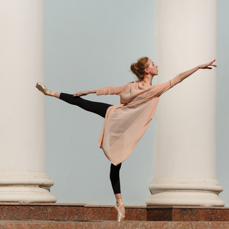 Slender young ballerina in pointe dancing in the street. Performance. The art of dance. Slender female feet. Classical ballet.の写真素材
