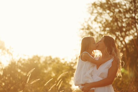 Family, mother holding daughter in her arms. A little girl kisses her mother. They are blondes. Family time together.の写真素材