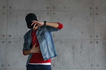Teenage boyfriend of denim jacket and red sweater dances hip-hop with baseball cap. Dynamics and plastic movement of modern dance. Youth fashion.の写真素材