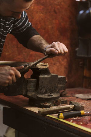 Man works in carpentry workshop. He files excess wood with an ax.の写真素材