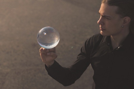 Contact juggling. Young guy is holding a glass ball on his fist. Mastery of Performanceの写真素材