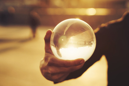 Contact juggling. Man balancing glass bowl on hand. Inverted reflection of person in ball. Mastery of representation. Picture at sunset. Trend viewの写真素材