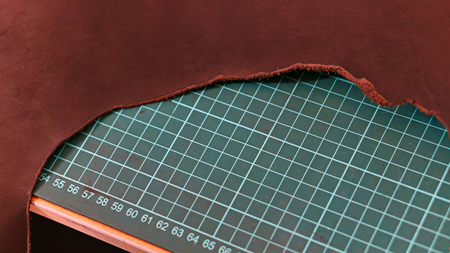 Cut brown leather with raw edges on cutting mat. Workpiece for product