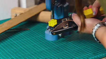 Tanner pierces holes in leather workpiece. Workflow in workshop