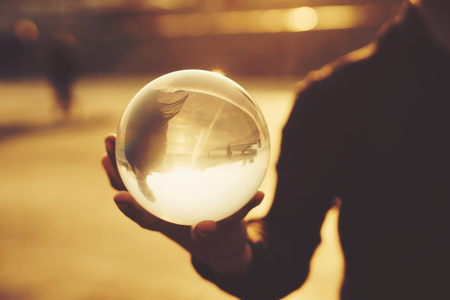 Contact juggling. Man balancing glass bowl on hand. Inverted reflection of person in ball. Mastery of representation. Photography at sunset. Trend viewの写真素材