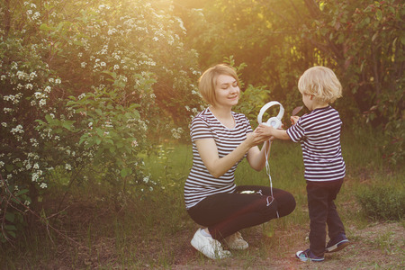 Mother and son in striped T-shirts. Woman is holding headphones. They are going to listen to music. Family time together.の写真素材