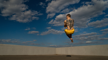Tricking on street. Martial arts. Man jumps barefooted. Shooted from bottom foreshortening against sky.の写真素材