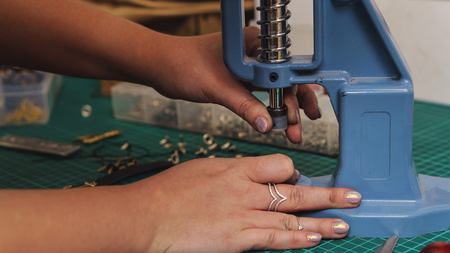 Tanner puts rivets on leather bracelet. Close-up photo. Process of working in workshop.の写真素材