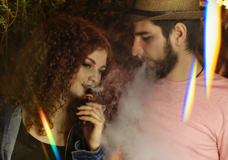 Loving couple on date. Guy and girlfriend smoke electronic cigarettes.の写真素材